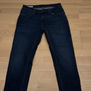 Mörkblå jeans från Zara, strl 42 - Snygga mörkblå jeans från Zara i klassisk femficksmodell. Jeansen har raka ben, normal passform och är tillverkade i slitstarkt denimtyg. Perfekta för dig som gillar en stilren look med mörka jeans och diskreta detaljer.