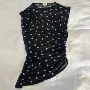 Svart mesh topp med vita prickar Abercrombie - Säljer en svart mesh topp från Abercrombie & Fitch i storlek XXS. Toppen har vita prickar över hela och är lätt transparent med en tight passform. Den är ärmlös och har en rund halsringning. Perfekt för dig som gillar coola mönster och trendiga detaljer. 