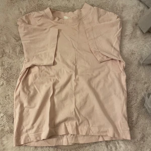 Ljusrosa basic t-shirt i bomull - En enkel och mjuk ljusrosa t-shirt med rund hals och korta ärmar. Perfekt för dig som gillar minimalistisk stil och vill ha en skön t-shirt i garderoben. Materialet är bomull och modellen har en normal passform.