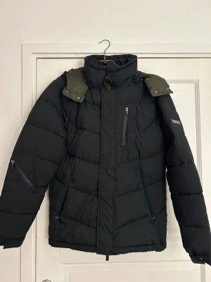 Scotch & Soda jacka - Oanvänd Skotch & Soda vinterjacka i storlek M. Prislappen är kvar. Jackan är svart och innerfodret är grönt. Luva, många fickor. Nypris 2299kr.