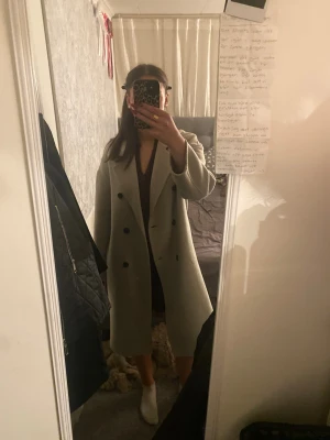 Beige kappa från Bik Bok - Säljer en stilren beige kappa från Bik Bok med dubbelknäppning och klassisk krage. Jackan har lång ärm och raka fickor på sidorna. Är i storlek S och bara använd fåtal gånger.