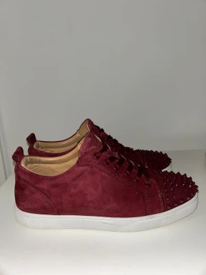 Christian Louboutin Vin Röda skor med spikar - Snygga vinröda Louboutin med spikar. Använda men fortfarande riktigt fräscha. Enda defekterna är creases, en något fläckig sula och mocka som tappat lite liv. Det går enkelt att fräscha upp igen. Skick visas i bilderna. Skick: 8/10 Tillbehör: Dust bags, extra snören, extra nittar Pris kan diskuteras 📦 Skickas eller möts upp