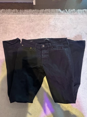 Svarta jeans från Jack & Jones - Svarta jeans från Jack & Jones Jeans Intelligence, modell Super Stretch. Klassisk femficksdesign med knapp och dragkedja i midjan. Jeansen har en rak passform och är tillverkade i stretchigt bomullsmaterial för extra komfort.