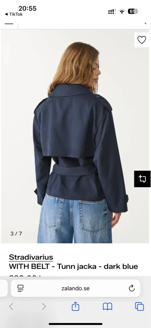 Mörkblå trenchcoat från Stradivarius(pris kan diskuteras) - Snygg mörkblå trenchcoat från Stradivarius med bälte i midjan och dubbelknäppning. Jackan har klassisk krage, axelklaffar och långa ärmar. Perfekt för lager-på-lager och ger en cool vibe till din outfit.