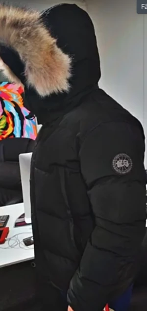 Svart dunjacka med päls från canda goose black - Säljer en svart dunjacka från Canada goose med stor huva och fluffig pälsdetalj. Jackan har ett snyggt emblem på ärmen och är riktigt tjock och varm, perfekt för kalla vinterdagar. Stängs med dragkedja och har lång ärm. Olika storlekar nyskick 