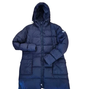 Mörkblå Moncler dunjacka med huva women 4 - Säljer en mörkblå dunjacka från Moncler med huva och stora fickor framtill. Jackan har quiltad design, lång ärm och dragkedja hela vägen upp. Perfekt för kalla dagar och har en snygg Moncler-logga på ärmen.