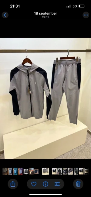 Under Armour träningsset med huva - Snyggt träningsset från Under Armour med jacka och byxa. Finns i helsvart, grå/svart och svart med grå detaljer. Jackan har huva och dragkedja, byxorna har smal passform och dragkedja vid benslut. Perfekt för dig som vill ha sportig och clean stil. FINNS I MÅNGA STORLEKAR OLIKA FÖRGER 