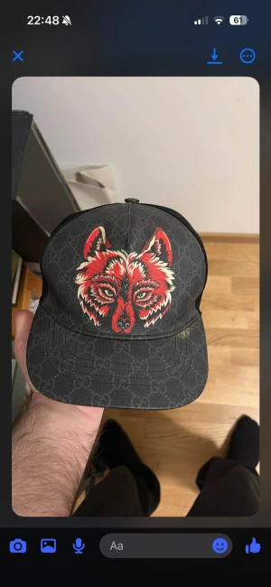 Gucci keps med röd vargtryck - Snygg svart keps från Gucci med klassiskt GG-mönster och ett fett rött vargtryck framtill. Kepsen har mesh på sidorna och justerbar rem bak med röd detalj. Perfekt för dig som vill sticka ut med designeraccessoar. Storlek L men passar mer som M pris kan diskuteras 