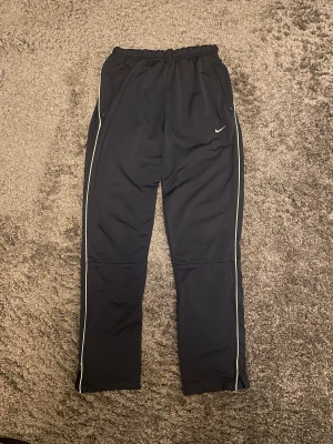 Nike vintage track pants mörkblå - Ganska lediga i passformen med dragkedja i botten av benen. Fraktar inom en dag. Kom gärna med rimliga prisförslag och skriv om du har frågor.