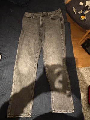 Mörkgråa jeans från Jack & Jones strl W31, L32. - Snygga mörkgråa jeans från Jack & Jones med klassisk femficksdesign och Clark Regular passform. Jeansen har en cool tvättad look och är tillverkade i slitstarkt denim. Perfekt för dig som gillar en enkel och stilren vibe. Storlek W31, L32.