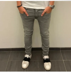 Replay ljusgrå skinny jeans - Säljer ett par ljusgrå Replay jeans i skinny fit med klassisk femficksdesign och diskreta slitningar. Jeansen har dragkedja i gylfen och svarta Replay-loggan på bakfickan. Snygga att matcha med sneakers och t-shirt för en clean look.