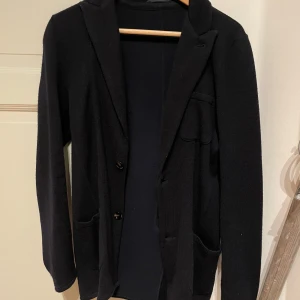 Mörkblå stickar kavaj från John Henric  - Tjena, Jag säljer nu en sjukt snygg mörkblå stickad kavaj från John Henric i storlek XS. Den är sparsamt använd. Hör gärna av dig vid frågor och funderingar!