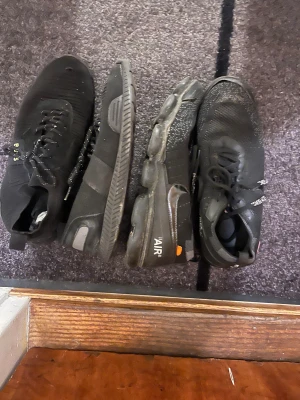 Svarta sneakers från BOSS & Nike Off-White - Två par svarta sneakers säljes! Ett par BOSS med stickad ovandel, snörning och reflekterande detaljer. Ett par Nike x Off-White Vapormax med textprint, snörning och unik bubblig sula. Båda har rund tå och platt sula, riktigt snygga och streetiga.