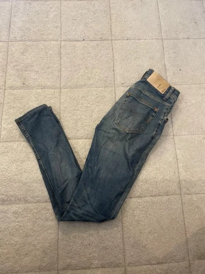 Blå jeans från tiger of sweden  - Snygga blå tiger of sweden jeans med klassisk femficksdesign och läderpatch bak i midjan. Jeansen har en rak och smal passform som sitter riktigt bra och är tillverkade i slitstarkt denim. Perfekta för dig som gillar en tidlös och cool stil.