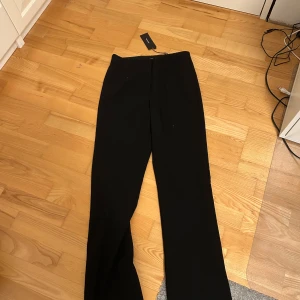 Svarta flared kostymbyxor Vero Moda - Svarta kostymbyxor från Vero Moda med hög midja och flared ben. Snyggt stilrena och raka i modellen. Materialet är mjukt och följsamt, vilket gör dem sköna att bära hela dagen. Helt oanvända. 