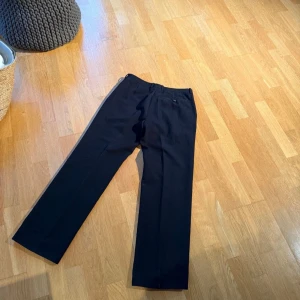 Miu Miu kostymbyxor  - Mörka kostymbyxor med en klassisk design. Byxorna har en tidlös stil som passar både till vardags och mer formella tillfällen