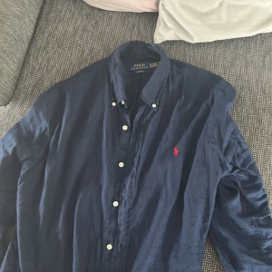 Marinblå skjorta från Polo Ralph Lauren - Snygg marinblå skjorta från Polo Ralph Lauren i custom fit med klassisk krage och knappar framtill. Skjortan är använd endast en gång och nypris är 2195kr.