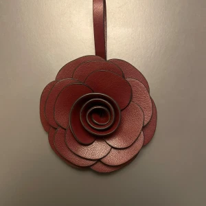 Väskdekoration - Väskdekoration att dekorera väskan med! En rosformad dekoration i vinröd färg. Passar perfekt för en elegant och chic look! Den ger väskan mera liv!