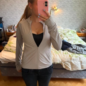 Ljusgrå ziptröja med lång ärm - Säljer en ljusgrå långärmad ziptröja i tunna träningsmatetial från unilqlo. Storlek xs 💗