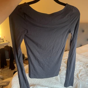 Mörkgrå långärmad topp med öppen rygg - Säljer en mörkgrå långärmad topp i mjuk bomull. Öppen i ryggen.  Storlek xxs men skulle nog säga att det är som en XS.