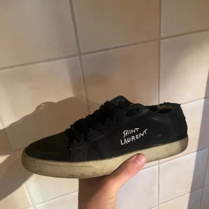 Svarta Saint Laurent sneakers - Säljer dessa tvärfeta saint laurents till ett sjukt billigt pris! Skorna är väldigt använda och tillkommer med hål i sulan vilket är anledning till det låga priset men de funkar fortfarande att använda under sommaren t.ex. Skriv dm för mer info👍