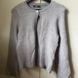 Grå kofta med knapp framtill - Koftan är aldrig använd men saknar prislapp. Den är fortfarande väldigt mjuk och ser ny ut!