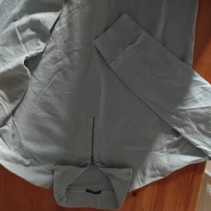 Ljusgrå half zip hoodie Stone Island - Säljer en ljusgrå hoodie från Stone Island med half zip framtill. Tröjan har långa ärmar och är tillverkad i 100% bomull vilket gör den riktigt skön och mjuk. Perfekt för dig som gillar stilrena och enkla plagg med coola detaljer. Ljusblå  färg använd 2 gånger storlek  är som en XL  fast det står XXL. 