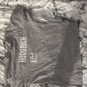 Grå HOODRICH t-shirt med tryck - Säljer en grå t-shirt från HOODRICH i storlek S. T-shirten har vit text och tryck både fram och bak med budskapet 'FROM NOTHING TO SOMETHING' och flera grafiska detaljer. Klassisk passform med rund hals och korta ärmar. 