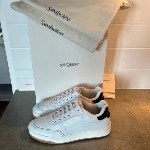 Saint Laurent sl/61 sneakers  - Snygga vita sneakers från Saint Laurent i lyxigt skinn med diskret guldtext på sidan. Klassisk modell med rund tå, snörning och svart detalj på hälen. Tillverkade i Italien och levereras med originalpåse och box. Perfekta för dig som gillar stilrena och exklusiva sneakers. Köpta för 850€ men passade inte, endast använda få gånger!