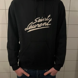 Saint Laurent hoodie - Riktigt fet och eftertraktad hoodie med saint laurent loggan. Storlek M, skick 10/10!! Modellen på bilden är 183cm. Är lite osäker på äktheten så därför är priset just nu på 999kr! Nypris runt 7000! Tveka inte med att ställa frågor!