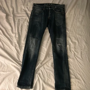 Mörkblå jeans från Jack & Jones - Snygga mörkblå jeans från Jack & Jones med slitna detaljer och klassisk femficksdesign. Jeansen har raka ben och ganska smal midja, med coola slitningar på både fram- och baksida. Perfekt för dig som gillar en avslappnad streetstil. Det är bara att höra av sig vid flera frågor🙌