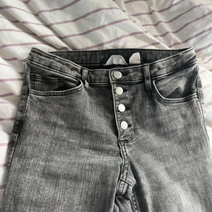 Grå bootcut jeans  - Säljer ett par grå lågmidjade  bootcut jeans med snygg tvätt , 4 silvriga knappar , storlek 170/15 år