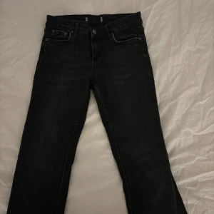 Svarta bootcut jeans - Snygga svarta jeans med bootcut passform och klassisk femficksdesign. Jeansen har en mörk tvätt och är tillverkade i jeansmaterial. Det finns ett litet hål jämte ena bakfickan men som inte stör oxh enkelt går att sy igen.