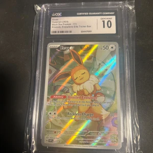 Eevee Black Star Promo (Prismatic Evolutions Elite Trainer Box) - Samlarvärd Pokémonkort med Eevee, Black Star Promo #173 från Prismatic Evolutions Elite Trainer Box. Kortet är graderat GEM MINT 10 av CGC och har en färgstark, holografisk design – perfekt för Pokémonfans och samlare!