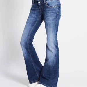 Blå bootcut jeans med utsvängda ben - Snygga blå jeans med bootcut och utsvängda ben. Klassisk femficksmodell med normal midja och lätt slitning på låren. Perfekta för dig som gillar en retrovibe och vill ha ett par jeans som sticker ut lite extra. Zipper ha gått sönder och är lite svårt och dra upp 