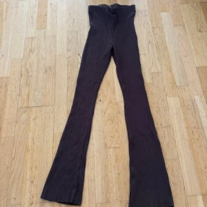 Mörkbruna ribbade bootcut byxor - Snygga mörkbruna ribbade byxor med bootcut-snitt och hög midja. Materialet är mjukt och stretchigt, vilket gör dem riktigt bekväma. Perfekta för dig som gillar en trendig och avslappnad stil.