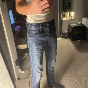   jeans från Jack & Jones - Snygga mörkblå Slim Glenn jeans från Jack & Jones med klassisk femficksdesign och smal passform. Jeansen har coola slitningar och kontrastsömmar, tillverkade i mjukt bomullsmaterial med stretch för extra komfort. Perfekt för dig som gillar en modern och stilren look.