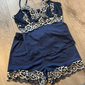 Marinblå spetslinnetopp från B&S - Säljer en marinblå linnetopp från B&S med tunna axelband och vacker spets i guld och beige över bysten. Toppen har en croppad passform och spetsdetaljer som ger en lyxig vibe. Perfekt att matcha med shorts eller jeans för en cool look.
