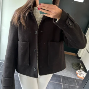 Svart kappa  - snygg svart kort kappa från nelly. använd några gånger men fortfarande fint skick. bild 4&5 ger rättvis bild av hur nopprig den är. fina detaljer med knapparna och på ärmarna. skulle säga att den sitter mer som en xs/s. passar till allt o perfekt inför höst och vinter