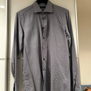 Mönstrad skjorta från Sand, stl 40 - Snygg skjorta från Sand i diskret rutigt mönster. Skjortan är blå och vit, har lång ärm och klassisk krage. Tillverkad i bomull och har knappar framtill. Perfekt för dig som gillar stilrena detaljer.