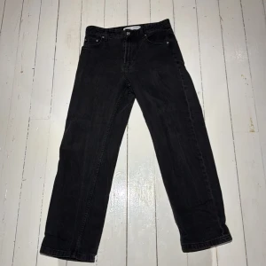 Svarta raka jeans från Bershka - Svarta jeans från Bershka i rak modell med klassisk femficksdesign. Jeansen har hög midja och är tillverkade i bomullstyg med en snygg mörk tvätt. Perfekta för en clean och stilren look. INGET FAST PRIS