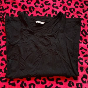 Svart linnetopp från Lindex  - Svart, enkel och klassisk linnetopp från Lindex. Modellen är ärmlös med rund halsringning och tillverkad i mjuk bomull som är skön mot huden. Perfekt att styla med jeans eller shorts för en chill look.