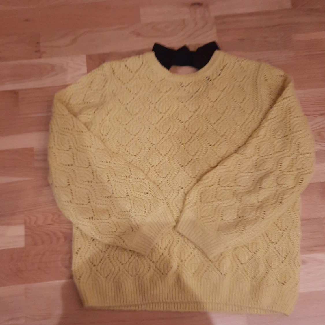 Gul stickad tröja med svart rosett