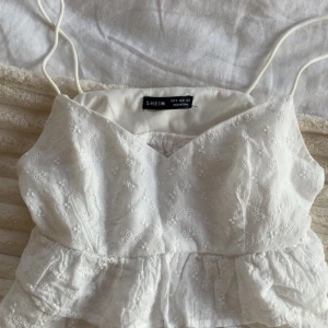 Söt vit blommig topp - Söt vit topp från SHEIN i storlek M, men passar xs-s. Toppen har tunna axelband, v-ringning, volang nedtill och små blommor över hela toppen. Sitter så fint på!💕💕