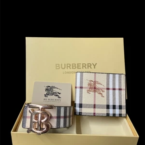 Burberry rutig bälte med B-spänne - Snyggt Burberry bälte med klassiskt rutigt mönster i beige, svart, vit och röd. Bältet har ett stort metallspänne med Burberrys ikoniska B-logga. Perfekt för dig som vill ha en lyxig och trendig accessoar med tydlig designerstil.