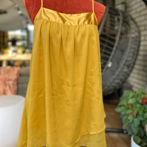 Gul kortklänning/linne från Vero Moda L - Guldfärgad linne med smala axelband. Linnet har en rak modell med en bredare kant upptill i ett glansigare tyg. Fint fall och dubbla lager. Polyester Längd: 72 cm Bystmått: 48 cm  Inga bilder när den sitter på mig! Katter finns i hemmet!