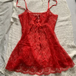 Röd spetsklänning!💋 - Aaasfin röd, kort klänning i spets med tunna axelband och snygg snörning framtill. Köpt i Berlin men har aldrig använts av mig. Storleken är uppskattningsvis L-XL men passar även större och mindre stlkr. Ett av axelbanden är knutet baktill då fästet var löst men det syns inte (bild 3). Skriv om du har frågor!💋