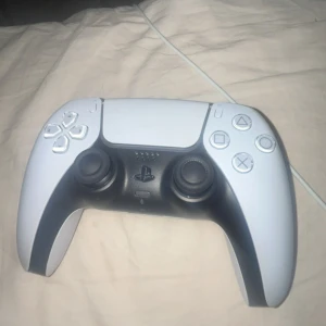 PlayStation 5 DualSense Wireless Controller - Snygg och välbevarad DualSense-kontroll till PlayStation 5. Fungerar trådlöst och har adaptiva triggers samt haptisk feedback. Inga synliga repor eller skador, knappar och spakar i fint skick. Perfekt för gamingupplevelse på PS5.
