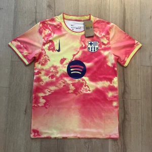 Barcelona x Nike Balde #3 fotbollströja - Barcelona fotbollströja med Balde #3, tillverkad i Nike Dri-Fit material. Tröjan har ett unikt mönster i rosa och gul med blå detaljer, klubbmärke på bröstet och Spotify-logga. Rund hals och korta ärmar, perfekt för dig som vill sticka ut på planen.
