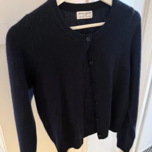 Mörkblå kofta 100% Kashmir - Snygg mörkblå kofta från Holly & Whyte by Lindex i 100% kashmir. Klassisk rund hals, långa ärmar och knappar framtill. Perfekt för dig som gillar mjuka och lyxiga material. Enkel och stilren design som funkar till många olika looks. Aldrig använd, säljer pga att den är för liten. Pris kan diskuteras.